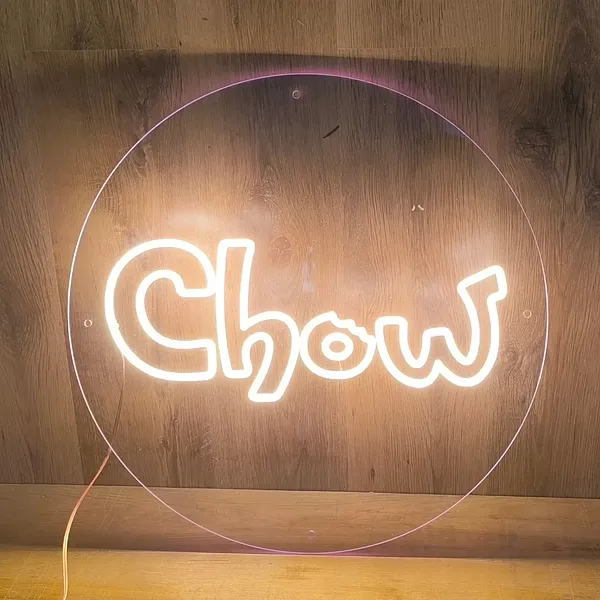 

LED neona logotips Chow ar siltu baltu spīdumu uz apaļas caurspīdīgas pamatnes.