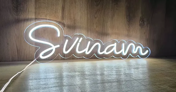LED neona izkārtne aukstā baltā krāsā ar uzrakstu „Svinam“, dekorācija īpašam pasākumam, pamatne — caurspīdīgs, glancēts, monolīts 6 mm biezs polikarbonāts.